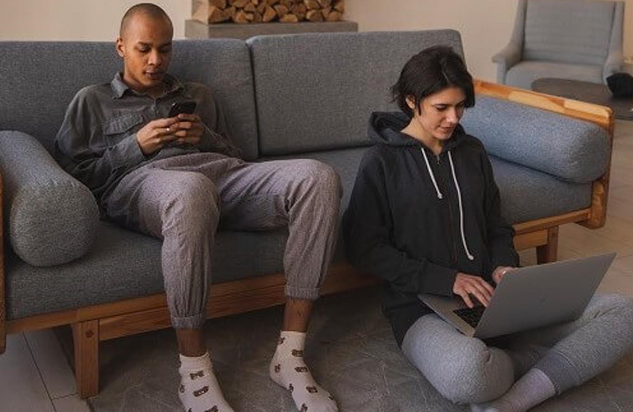 Couple at home on phone and laptop